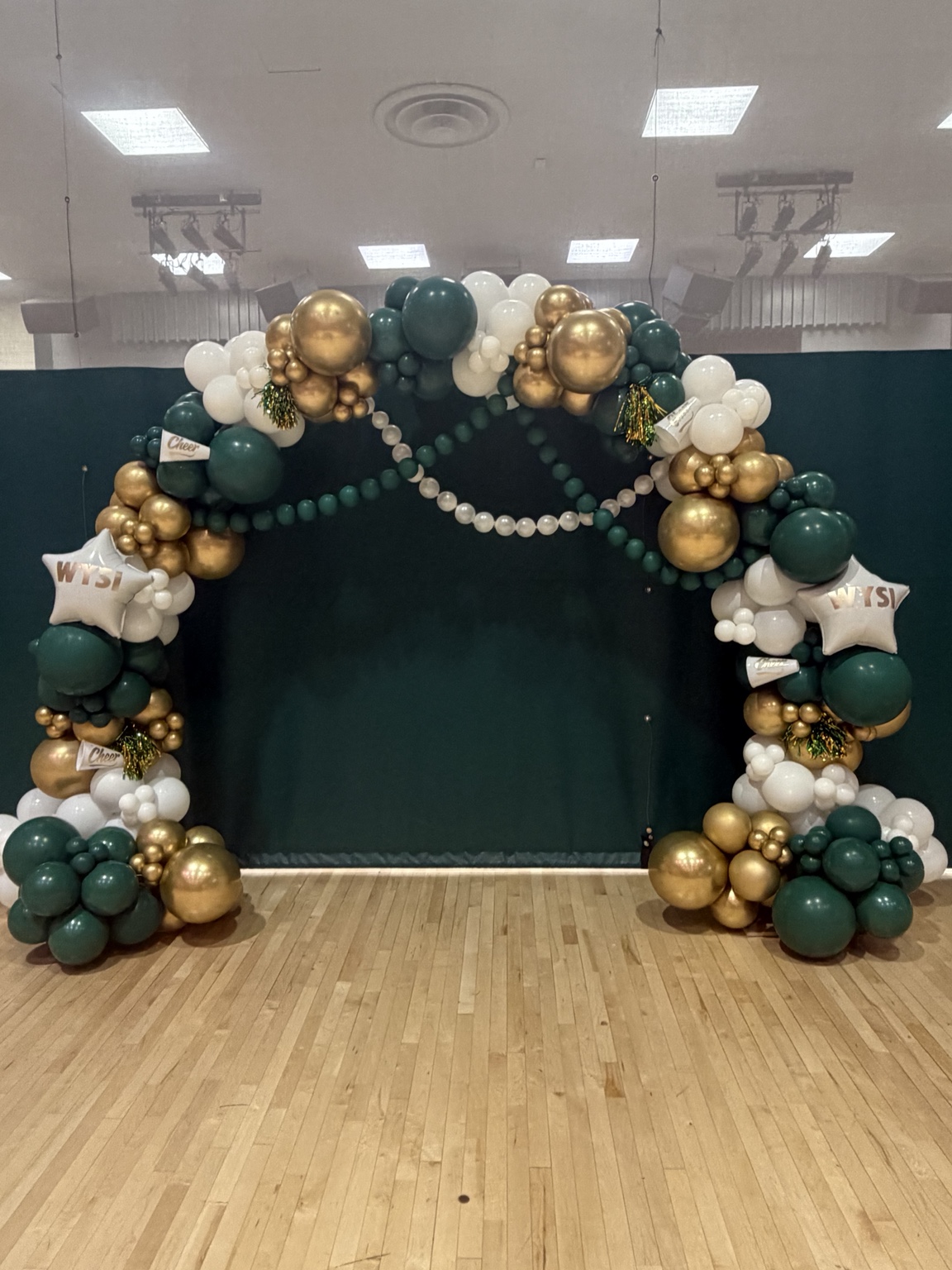 Large green, gold and white balloon arch installation by Bubble Bloom Collective