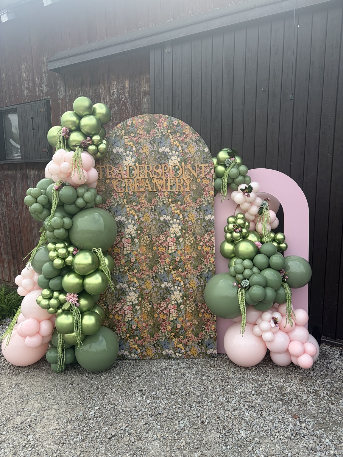 Botanical green and pink balloon installation framing a custom Traders Point Creamery floral backdrop