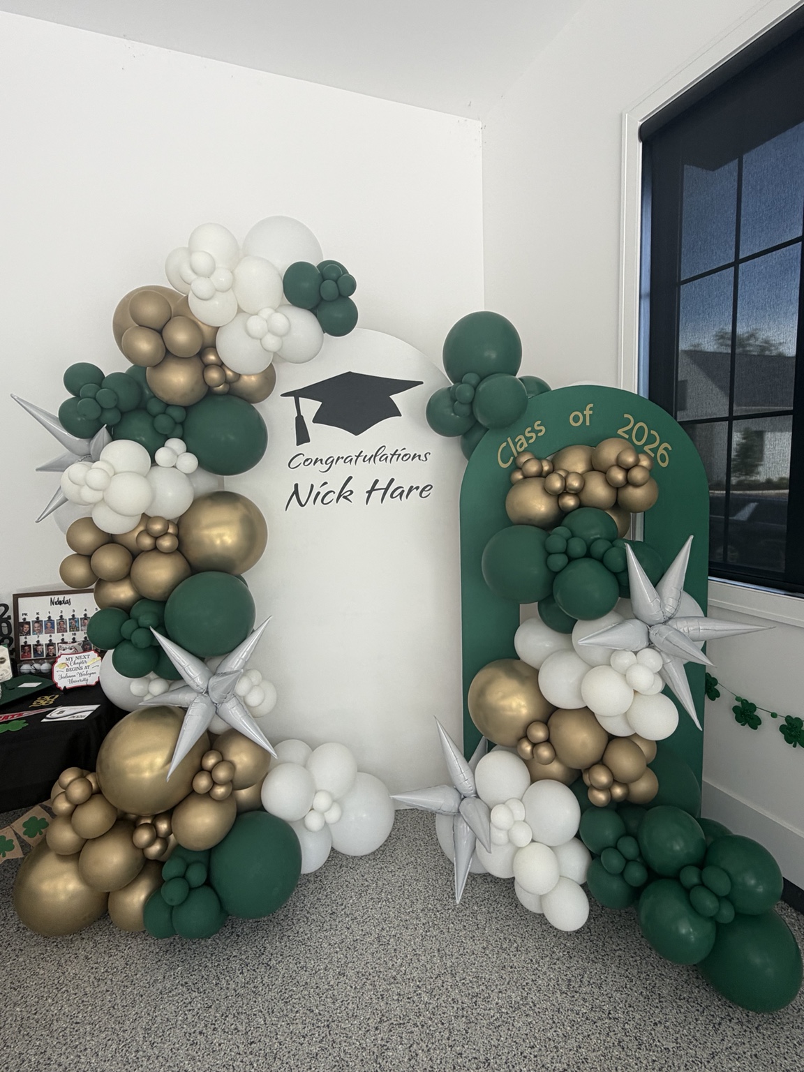 Sage, green and gold balloon arch installation with custom graduation signs