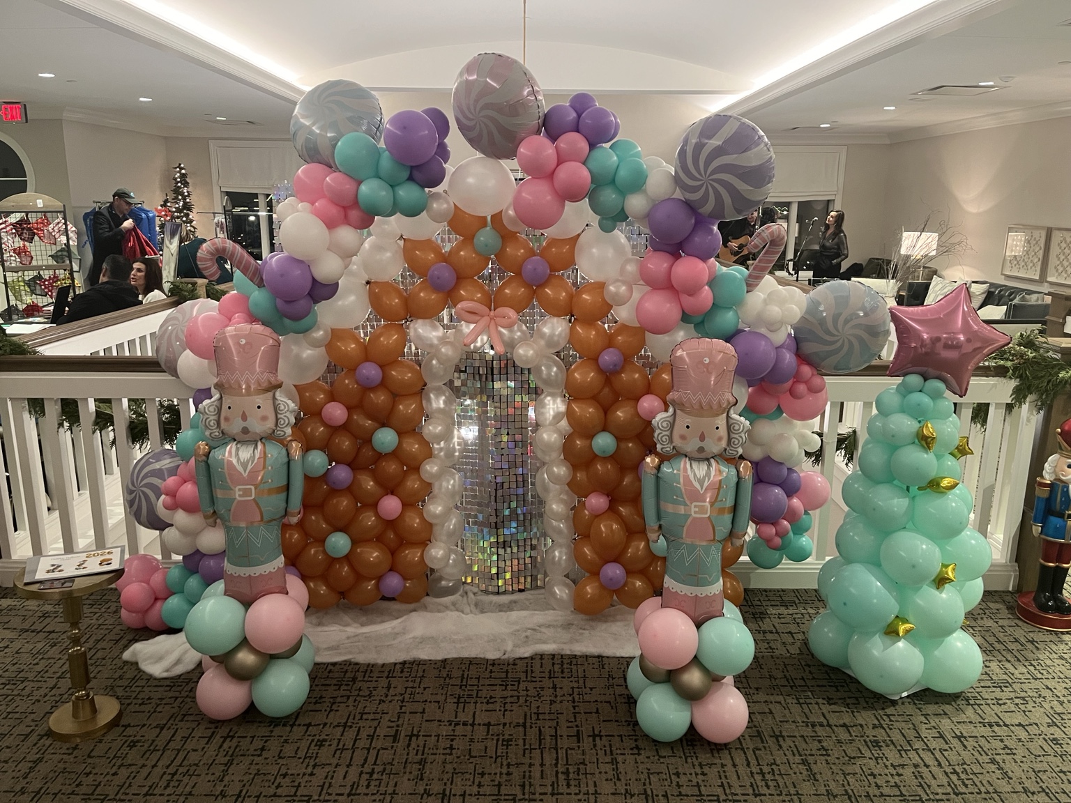 Pastel candy-themed balloon installation with oversized peppermint balloons, nutcrackers and shimmering doorway
