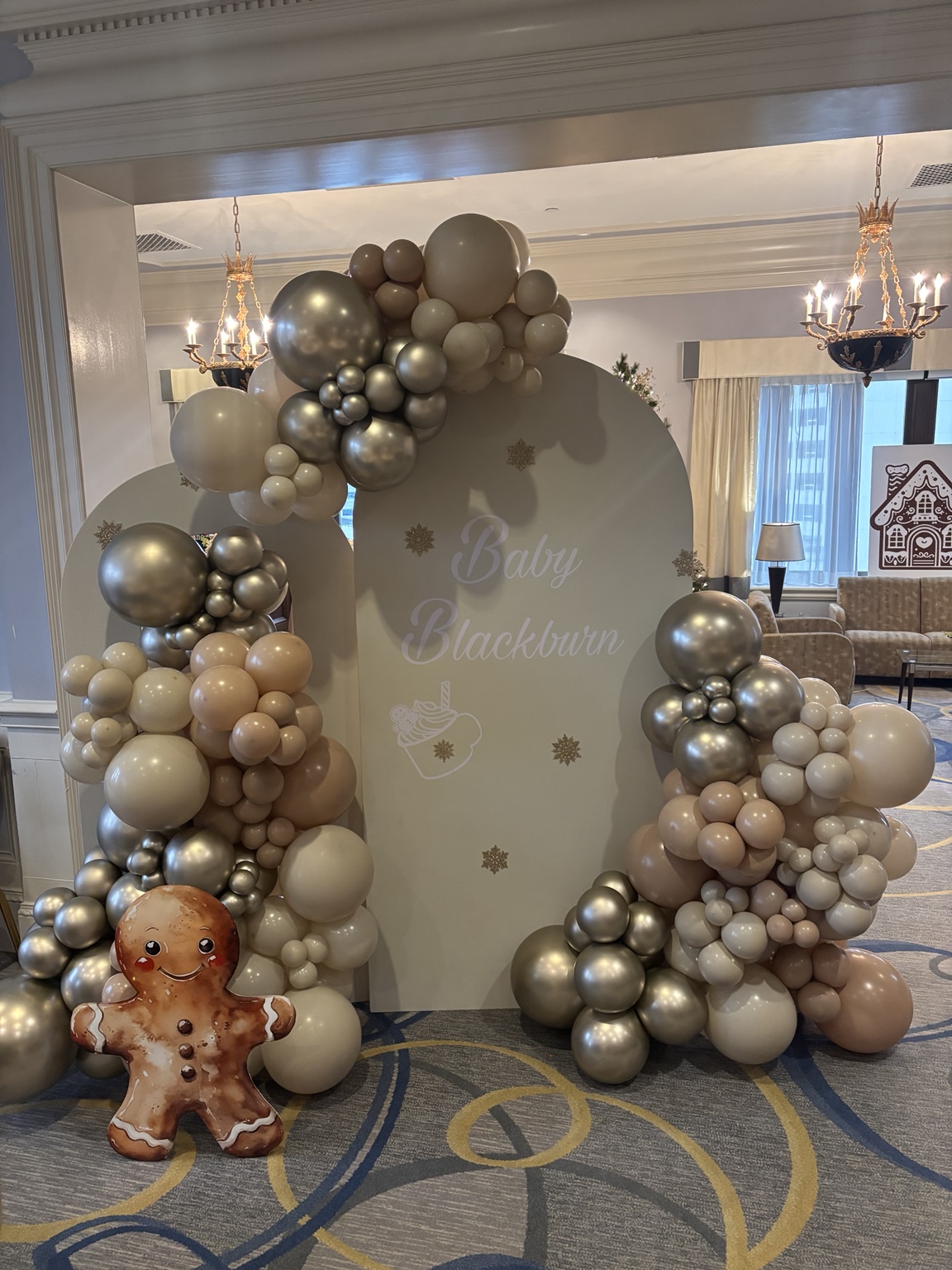 Champagne silver, ivory and warm neutral balloon installations around layered custom Baby Blackburn backdrops and a gingerbread figure